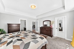 Bedroom featuring light gray wall paint, recessed ceiling with a central flush-mount light fixture, and plush carpet flooring - 
