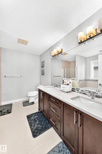 Bathroom featuring a dual vanity with dark wood-finish cabinetry, white countertops, and undermount sinks - 3672 Claxton Place, Edmonton, AB 