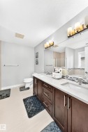 Bathroom featuring a dual vanity with dark wood-finish cabinetry, white countertops, and undermount sinks - 