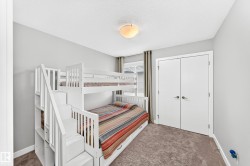 Room featuring light gray walls, textured carpet flooring, a flush-mount ceiling light, and white bi-fold closet doors with brushed nickel hardware - 