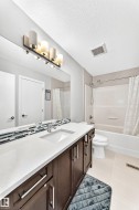 Full bathroom featuring a dark wood-finish vanity with a white countertop and undermount sink - 