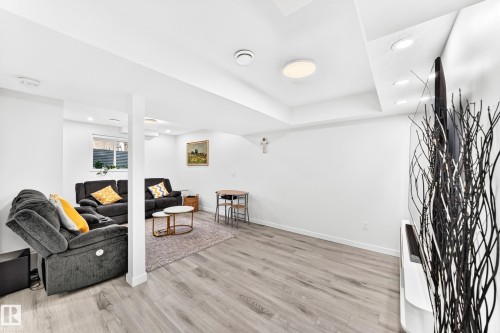Open-concept living area featuring light wood-finish flooring, recessed ceiling lighting, and a neutral color palette - 3672 Claxton Place, Edmonton, AB 