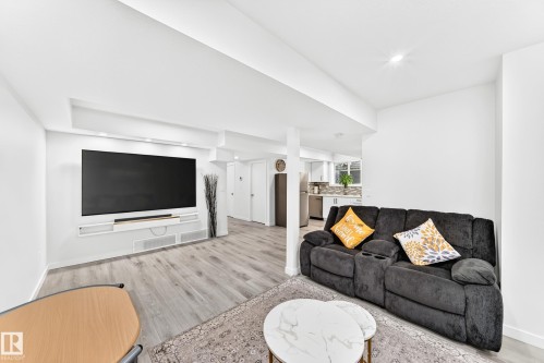 Open-concept living area with light wood-finish flooring, a built-in media console, recessed lighting, and a white color palette - 3672 Claxton Place, Edmonton, AB 
