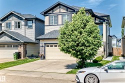 Contemporary two-story residence featuring a prominent front-facing gable, light-toned siding, and dark trim accents - 