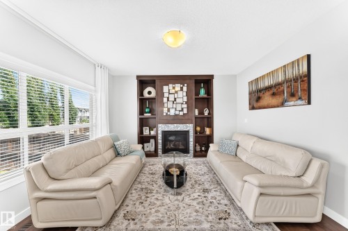 Living area featuring a floor-to-ceiling built-in fireplace with a stone surround and dark wood shelving - 3672 Claxton Place, Edmonton, AB 