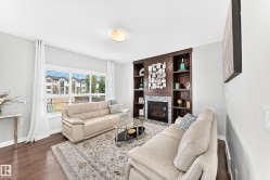 Living area featuring a built-in dark wood entertainment unit with shelving, a recessed fireplace with tile surround, and large windows with privacy blinds - 