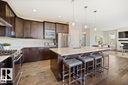 Kitchen island featuring a white countertop, built-in sink, and three pendant lights - 1004 Huckell Pl Sw, Edmonton, AB - Indoor Photo Showing Kitchen With Double Sink With Upgraded Kitchen