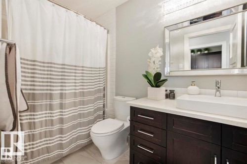 Vanity featuring dark wood-finish cabinetry, a white countertop, and a vessel sink with a chrome faucet - 1004 Huckell Pl Sw, Edmonton, AB - Indoor Photo Showing Bathroom