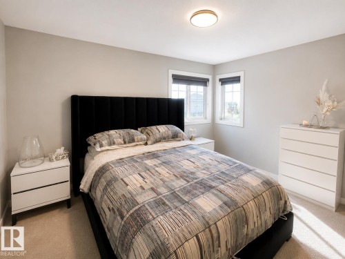Bedroom with light neutral walls, two windows with dark roller shades, and a flush mount ceiling light fixture - 1004 Huckell Pl Sw, Edmonton, AB - Indoor Photo Showing Bedroom