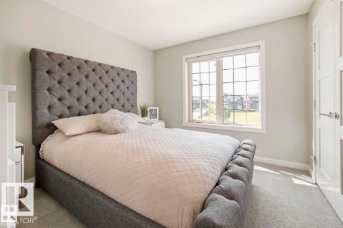Bedroom featuring light gray wall paint, light-colored carpeting, a large multipane window, white trim, and a built-in closet with panel doors - 1004 Huckell Pl Sw, Edmonton, AB - Indoor Photo Showing Bedroom