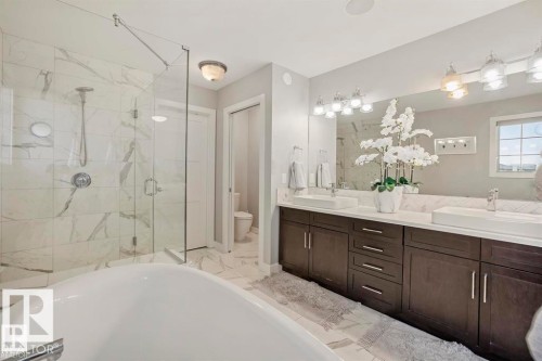 Bathroom featuring a freestanding tub, glass-enclosed shower with tiled walls, and a double vanity with two vessel sinks - 1004 Huckell Pl Sw, Edmonton, AB - Indoor Photo Showing Bathroom