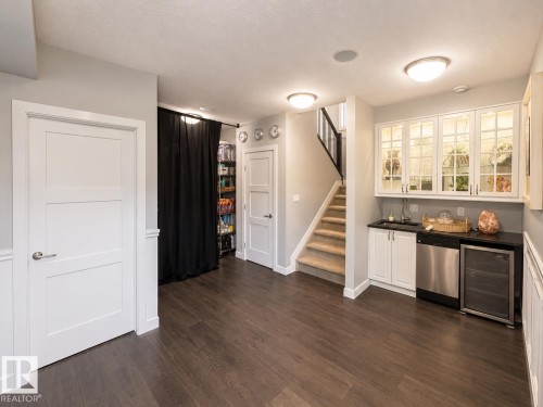 Wet bar with under-cabinet lighting, glass-front upper cabinetry, and a beverage refrigerator - 1004 Huckell Pl Sw, Edmonton, AB - Indoor