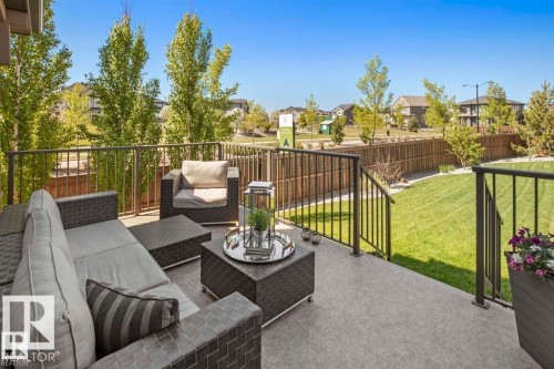 Private concrete patio featuring black metal railings and direct access to a manicured lawn - 1004 Huckell Pl Sw, Edmonton, AB - Outdoor