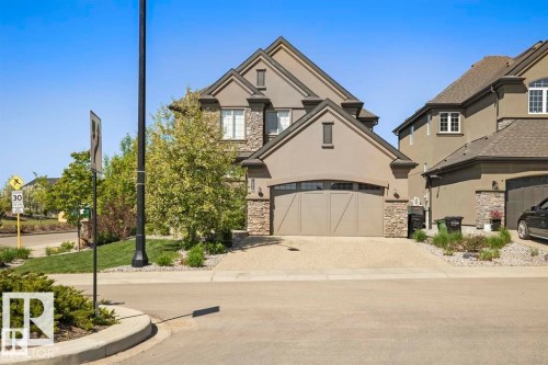 Stucco and stone facade home featuring an attached double-door garage with an arched transom window - 1004 Huckell Pl Sw, Edmonton, AB - Outdoor