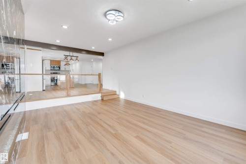 Bright living area featuring wood-finish flooring, recessed lighting, and a modern ceiling fixture - 5512 150 Avenue, Edmonton, AB 