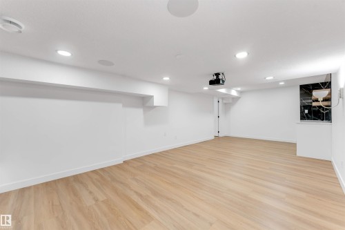 Spacious recreation room featuring light wood-finish flooring and recessed lighting - 5512 150 Avenue, Edmonton, AB 