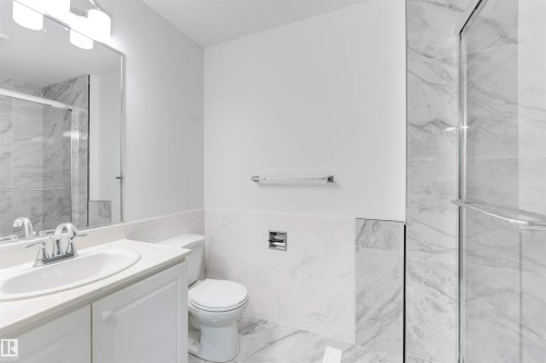 Contemporary bathroom featuring a white vanity with an integrated sink, polished chrome faucet, and a large wall-mounted mirror - 5512 150 Avenue, Edmonton, AB 