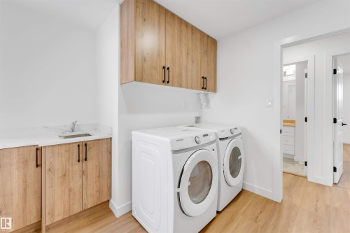 Utility room featuring wood-finish cabinetry, a white countertop with an undermount sink, and light wood-finish flooring - 5512 150 Avenue, Edmonton, AB 