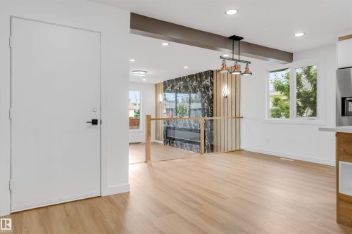 Open-concept living space featuring wood-finish flooring, recessed lighting, and large windows - 5512 150 Avenue, Edmonton, AB 