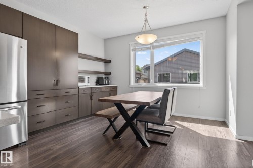 Kitchen area featuring wood-finish flooring, ample cabinetry with dark pulls, white countertops, and a large window - 3456 Cutler Crescent, Edmonton, AB - Indoor Photo Showing Dining Room