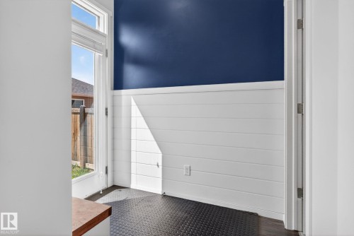 Entryway featuring a floor-to-ceiling glass panel door, white shiplap paneling, a deep blue accent wall, and dark textured flooring - 3456 Cutler Crescent, Edmonton, AB - Indoor Photo Showing Other Room