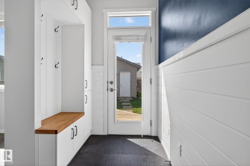 Entryway mudroom featuring white built-in cabinetry, a wood-finish bench, and black coat hooks - 3456 Cutler Crescent, Edmonton, AB - Indoor Photo Showing Other Room