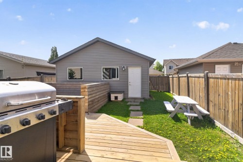 Expansive outdoor space featuring a large wooden deck, fenced yard, stepping stone pathway, and a detached structure with siding - 3456 Cutler Crescent, Edmonton, AB - Outdoor With Exterior