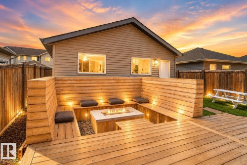 Expansive outdoor deck featuring built-in wooden seating with integrated lighting, a central fire pit, and a fenced perimeter - 3456 Cutler Crescent, Edmonton, AB - Outdoor With Deck Patio Veranda With Exterior