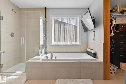 Recessed bathtub with tile surround, adjacent to a glass-enclosed shower featuring a handheld shower head and rainfall shower head - 3456 Cutler Crescent, Edmonton, AB - Indoor Photo Showing Bathroom