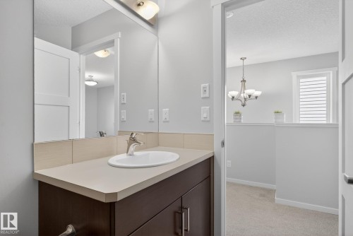 Vanity with an integrated oval sink and chrome faucet, set against a full-width mirror - 3456 Cutler Crescent, Edmonton, AB - Indoor Photo Showing Bathroom