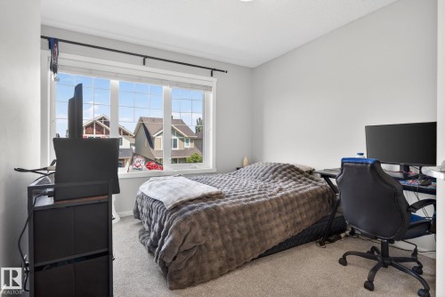 Bright room featuring a large window with grid pattern, neutral wall tones, and textured carpeting - 3456 Cutler Crescent, Edmonton, AB - Indoor Photo Showing Bedroom