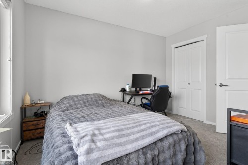 Carpeted room featuring a window with white trim, light gray walls, a bi-fold closet door, and a paneled interior door with chrome hardware - 3456 Cutler Crescent, Edmonton, AB - Indoor Photo Showing Bedroom