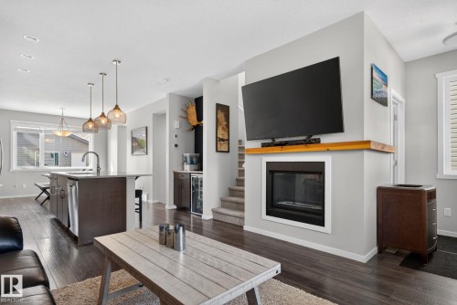 Living area featuring a built-in fireplace with a wooden mantel, dark wood-finish flooring, and light-toned walls - 3456 Cutler Crescent, Edmonton, AB - Indoor With Fireplace