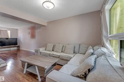 Spacious living area featuring wood-finish flooring, a contemporary flush-mount ceiling light, and ample natural light from the large window - 