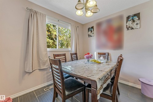 Dining area featuring a contemporary chandelier, multiple windows, and wood-finish flooring - 24 1651 46 Street, Edmonton, AB 