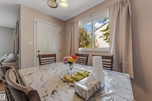 Dining area featuring an overhead light fixture, a window with exterior tree and building views, and light-toned walls - 24 1651 46 Street, Edmonton, AB 