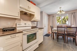 Kitchen featuring white cabinetry, dark countertops, a white electric range, and tile flooring - 