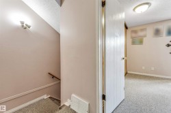 Interior space featuring neutral wall paint, a textured ceiling, and a doorway leading to a carpeted room - 