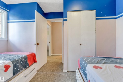 Carpeted room featuring a white-framed window, bi-fold closet doors, and painted walls - 24 1651 46 Street, Edmonton, AB 