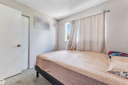 Bedroom featuring a window with natural light, textured ceiling, light-toned wall paint, and gray carpet flooring - 