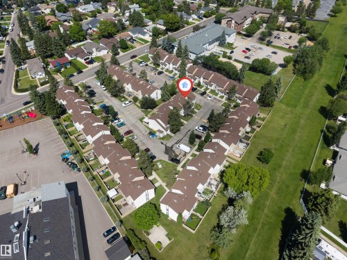 Aerial view of a residential complex with brown-roofed townhomes, featuring multiple private patios, individual parking spaces, mature landscaping, and a central courtyard area - 24 1651 46 Street, Edmonton, AB 