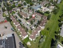 Aerial view of a residential complex with brown-roofed townhomes, featuring multiple private patios, individual parking spaces, mature landscaping, and a central courtyard area - 24 1651 46 Street, Edmonton, AB 