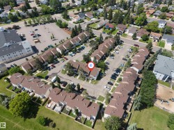 Townhome community featuring brown shingle roofs, individual patios, paved parking areas, and surrounding green spaces - 