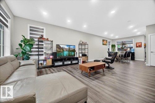 Open-concept living area featuring wood-finish flooring, recessed lighting, and large windows with blinds - 18139 75 Street, Edmonton, AB 