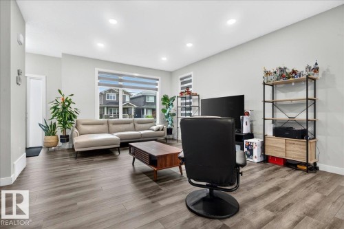 Spacious living area featuring wood-finish flooring, recessed lighting, and a large window with horizontal blinds - 18139 75 Street, Edmonton, AB 