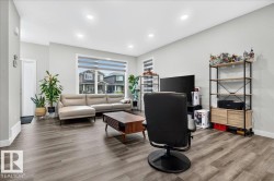 Spacious living area featuring wood-finish flooring, recessed lighting, and a large window with horizontal blinds - 