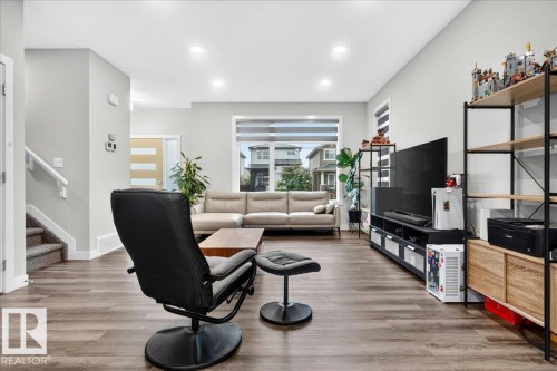 Living area featuring wood-finish flooring, recessed lighting, and large windows with blinds - 18139 75 Street, Edmonton, AB 