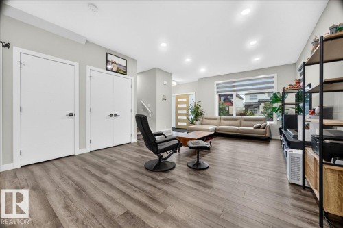 Spacious living area featuring wood-finish flooring, recessed lighting, and a large window with horizontal blinds - 18139 75 Street, Edmonton, AB 