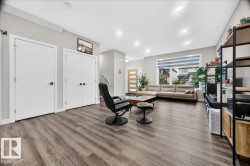 Spacious living area featuring wood-finish flooring, recessed lighting, and a large window with horizontal blinds - 