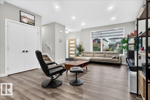 Spacious living area featuring wood-finish flooring, recessed lighting, and a large window with horizontal blinds - 18139 75 Street, Edmonton, AB 